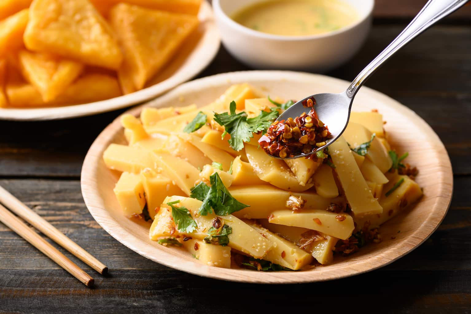 a Thai spicy salad featuring Burmese tofu sits in front of a plate of tofu triangles